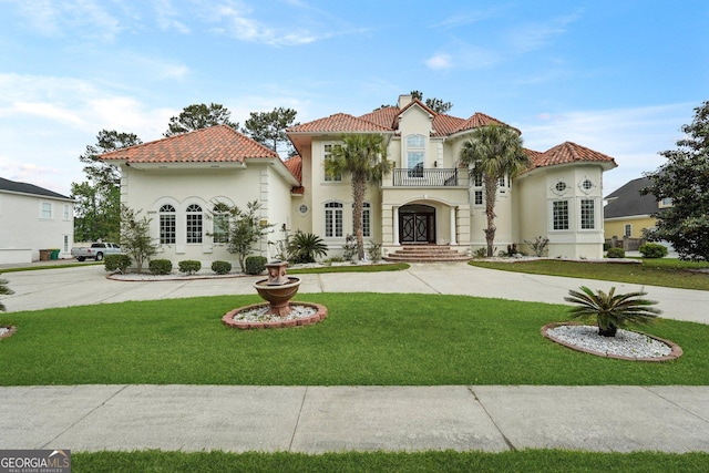 mediterranean / spanish home featuring stucco siding, a balcony, a front lawn, and a tile roof