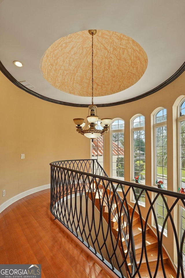 staircase featuring a chandelier, hardwood / wood-style floors, baseboards, recessed lighting, and ornamental molding
