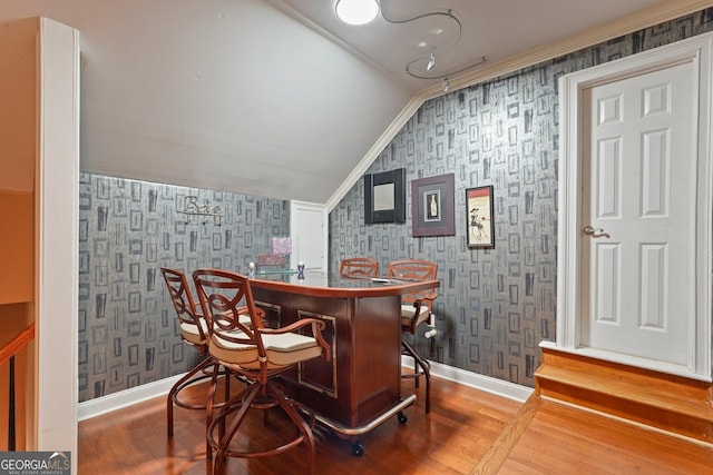 bar with baseboards, wallpapered walls, wood finished floors, and vaulted ceiling