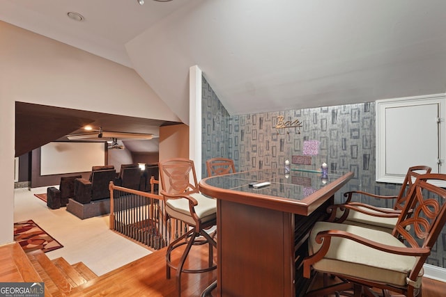 bar featuring lofted ceiling and wallpapered walls