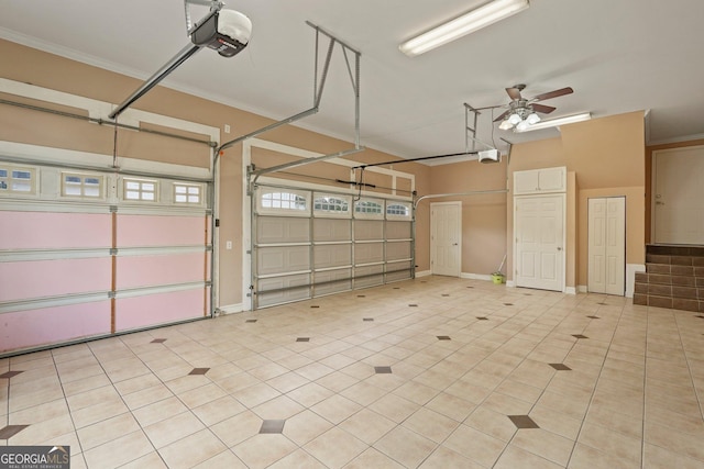 garage featuring baseboards, a garage door opener, and a ceiling fan