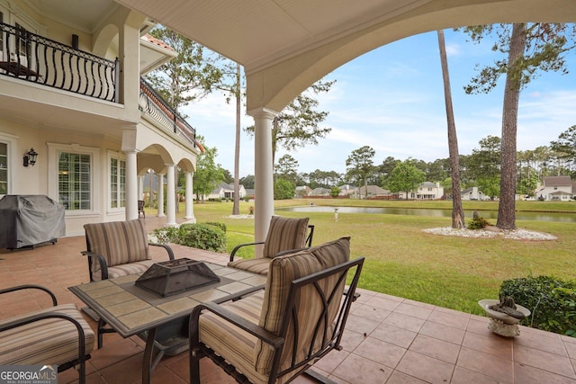 view of patio / terrace featuring a grill, an outdoor fire pit, a balcony, and a water view