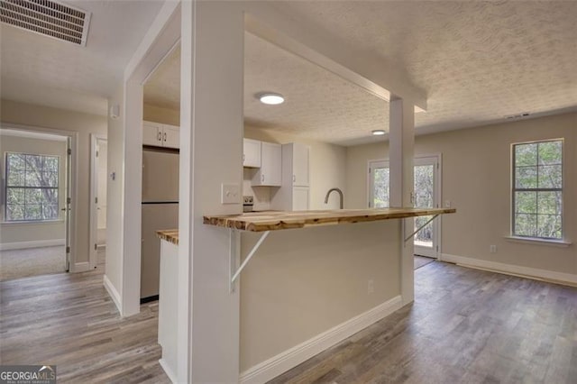479 Lakeview Dr, Dahlonega, GA 30533 - kitchen featuring white cabinets, wood finished floors, visible vents, freestanding refrigerator, and a textured ceiling