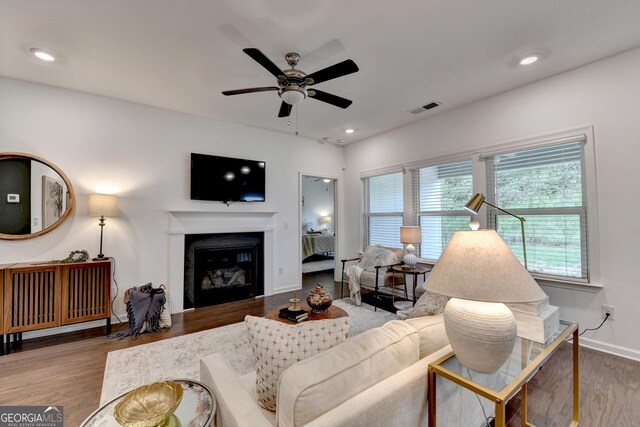 living room featuring healthy amount of natural light, ceiling fan, wood finished floors, a glass covered fireplace, and recessed lighting