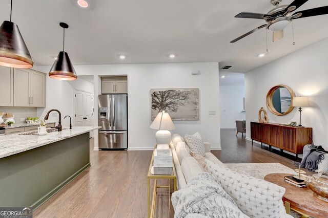 living room with a ceiling fan, wood finished floors, recessed lighting, and baseboards