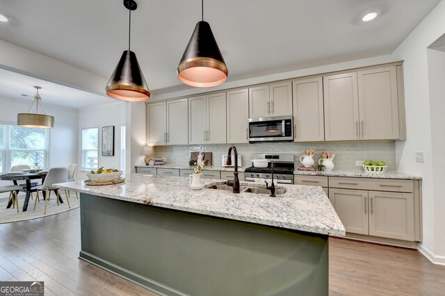 kitchen with stainless steel appliances, a sink, decorative backsplash, wood finished floors, and recessed lighting