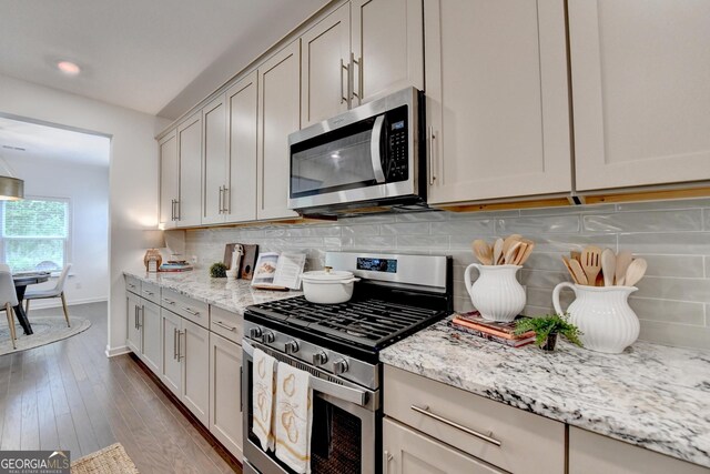 kitchen featuring stainless steel appliances, light stone counters, tasteful backsplash, and baseboards