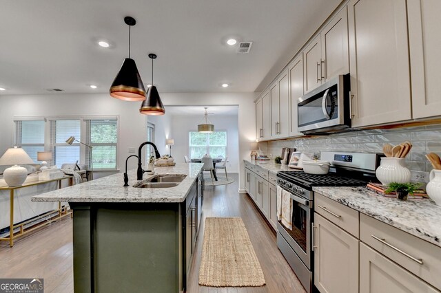 kitchen featuring appliances with stainless steel finishes, a sink, open floor plan, healthy amount of natural light, and recessed lighting