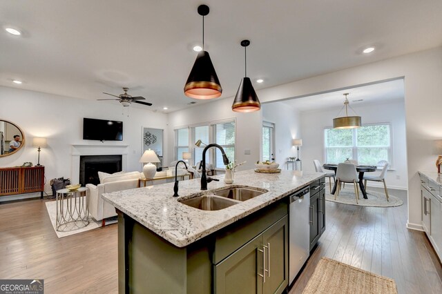 kitchen featuring a sink, dishwasher, a ceiling fan, a fireplace, and dark wood finished floors