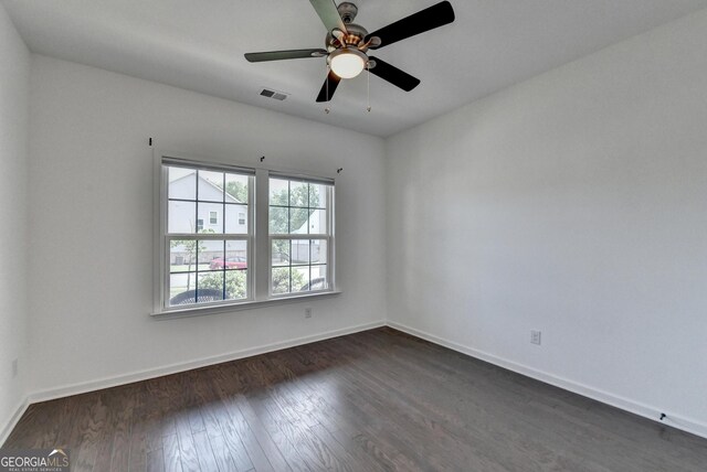 unfurnished room featuring dark wood finished floors, baseboards, and a ceiling fan