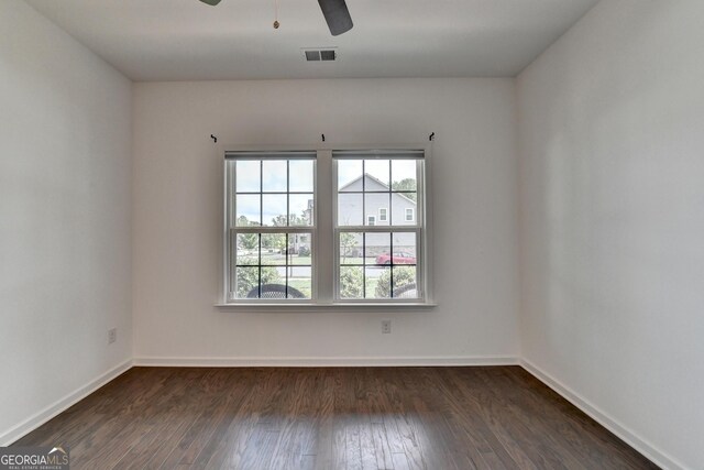 empty room with dark wood-style floors, baseboards, and a ceiling fan