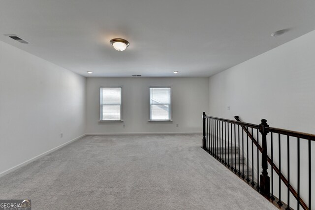 spare room featuring baseboards and light carpet