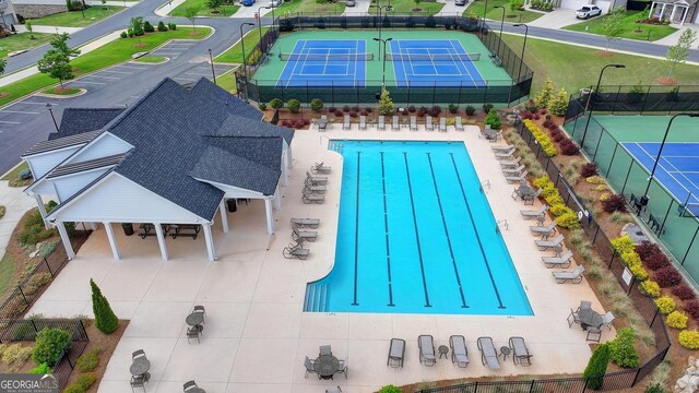 community pool with fence and a tennis court