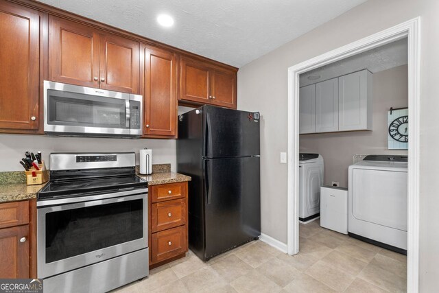 kitchen with appliances with stainless steel finishes, brown cabinets, washer and clothes dryer, and light stone countertops