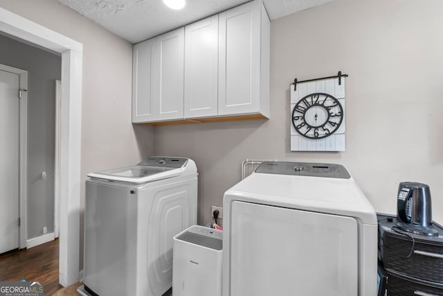 washroom featuring washer and dryer, a textured ceiling, cabinet space, and wood finished floors