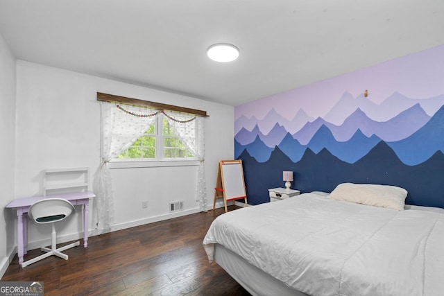 bedroom with visible vents, an accent wall, wood finished floors, and baseboards