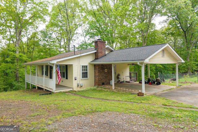 view of front of property featuring a porch, an attached carport, ceiling fan, driveway, and a chimney