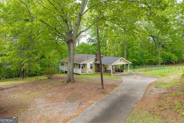 single story home with a chimney, a porch, fence, aphalt driveway, and an attached carport
