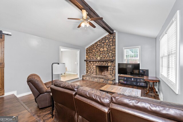 living room featuring a barn door, a fireplace, wood finished floors, a ceiling fan, and vaulted ceiling with beams