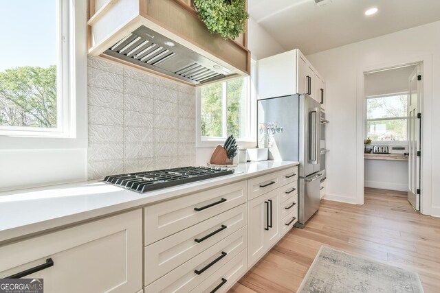 5315 Hendrix Rd, Cumming, GA 30040 - kitchen featuring appliances with stainless steel finishes, light countertops, decorative backsplash, a healthy amount of sunlight, and custom exhaust hood