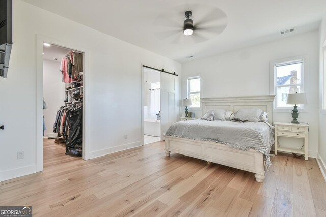 5315 Hendrix Rd, Cumming, GA 30040 - bedroom with visible vents, a closet, a walk in closet, a barn door, and light wood-style flooring
