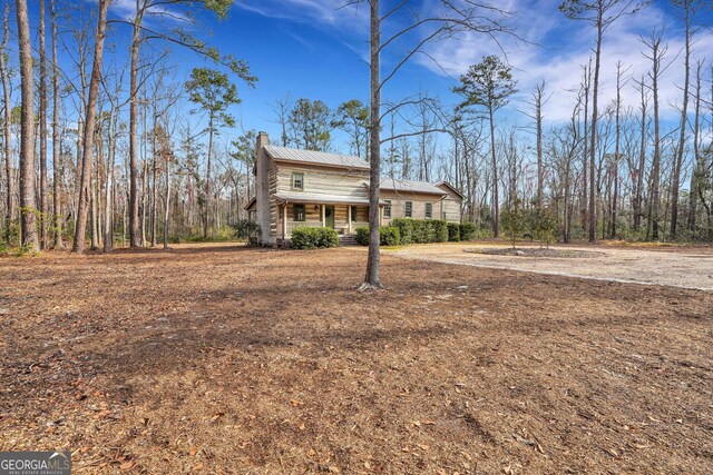 590 Dogwood Way, Richmond Hill, GA 31324 - traditional-style house with metal roof, covered porch, and a chimney