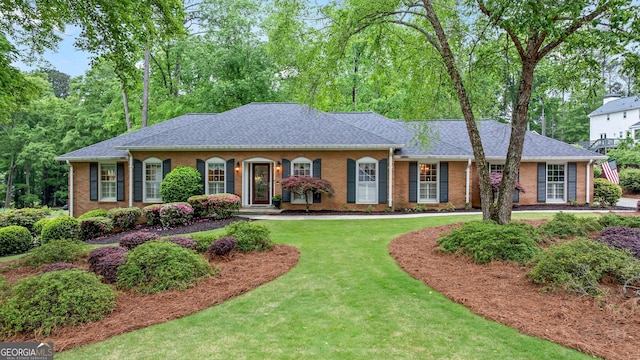 view of front facade featuring brick siding, a shingled roof, and a front lawn