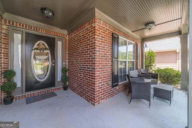 view of exterior entry featuring a porch and brick siding