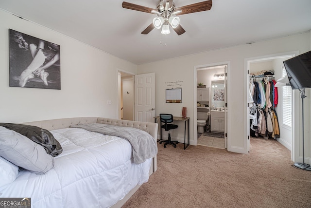bedroom with light carpet, connected bathroom, a walk in closet, a closet, and baseboards