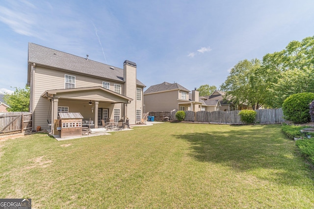 rear view of house with a fenced backyard, a yard, a ceiling fan, and a patio