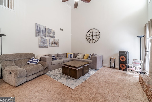 living area featuring visible vents, light carpet, a high ceiling, and ceiling fan