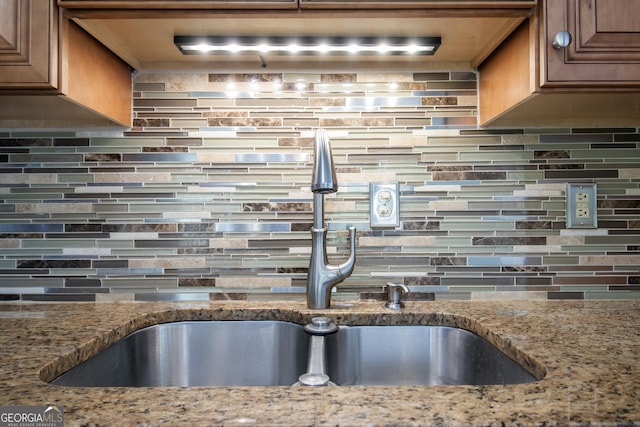 kitchen featuring a sink, tasteful backsplash, and light stone counters