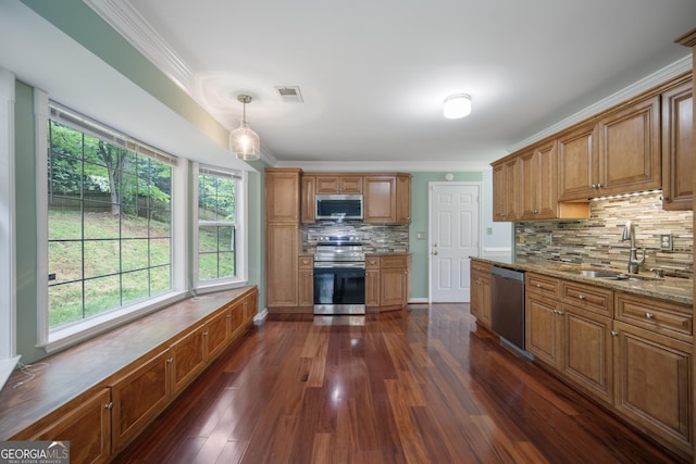 kitchen with stainless steel appliances, a sink, backsplash, brown cabinets, and ornamental molding