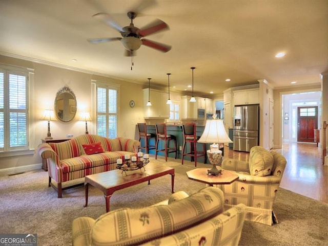 carpeted living area featuring ornamental molding, a ceiling fan, stairs, recessed lighting, and baseboards