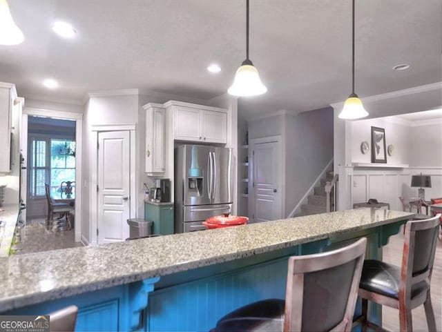 dining space featuring a decorative wall, ornamental molding, wood finished floors, and wainscoting