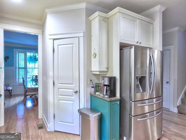 kitchen featuring stainless steel fridge with ice dispenser, crown molding, white cabinetry, light stone countertops, and pendant lighting