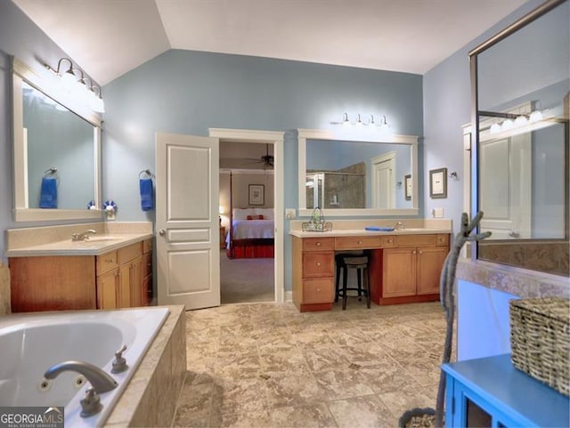 ensuite bathroom with vaulted ceiling, a ceiling fan, a jetted tub, and two vanities