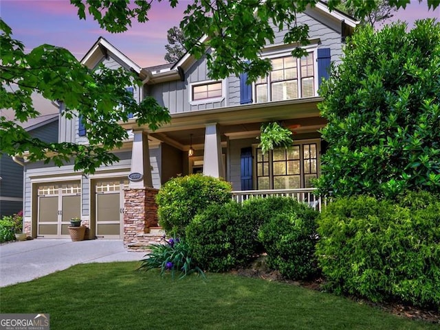 craftsman-style house with board and batten siding, an attached garage, covered porch, and concrete driveway