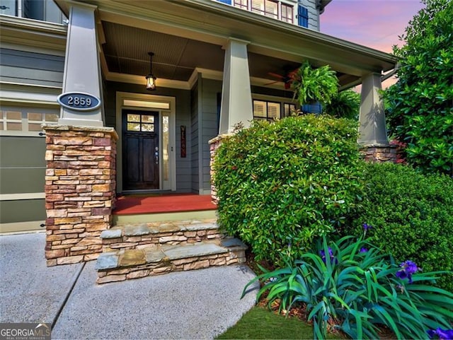 craftsman-style house featuring driveway, covered porch, board and batten siding, a front lawn, and stone siding