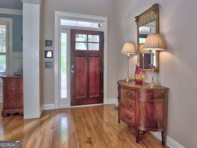 hall featuring wood finished floors, wainscoting, and ornamental molding