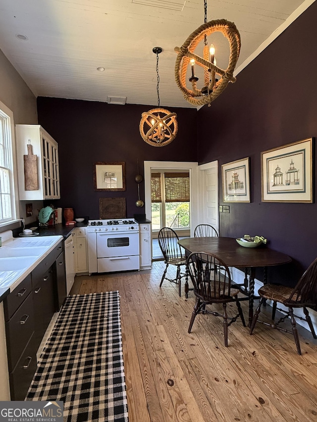 kitchen featuring white cabinetry, light wood finished floors, a chandelier, and white appliances