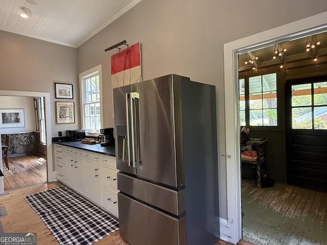 kitchen featuring light wood-type flooring, dark countertops, a wealth of natural light, and stainless steel fridge with ice dispenser