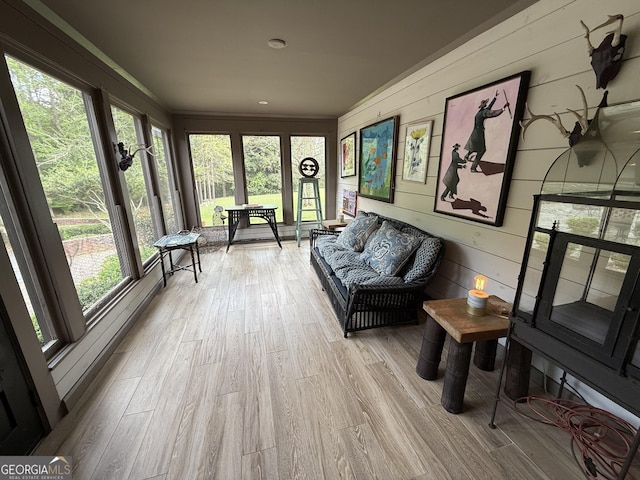 sunroom with wood walls, a healthy amount of sunlight, and wood finished floors