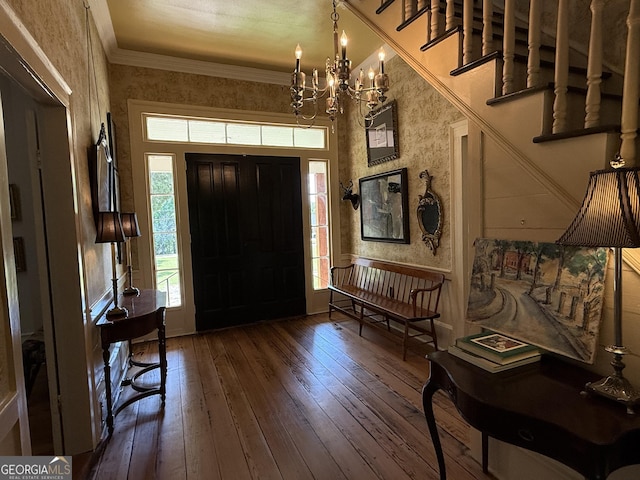 foyer with hardwood / wood-style floors, baseboards, a chandelier, and crown molding