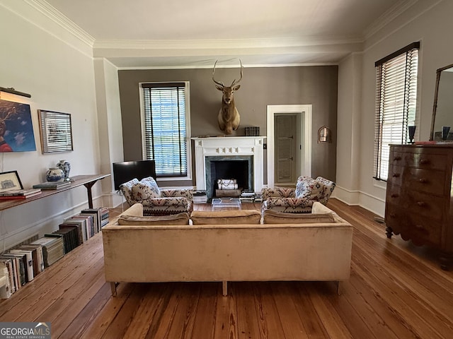 living area featuring baseboards, a fireplace, ornamental molding, and dark wood finished floors