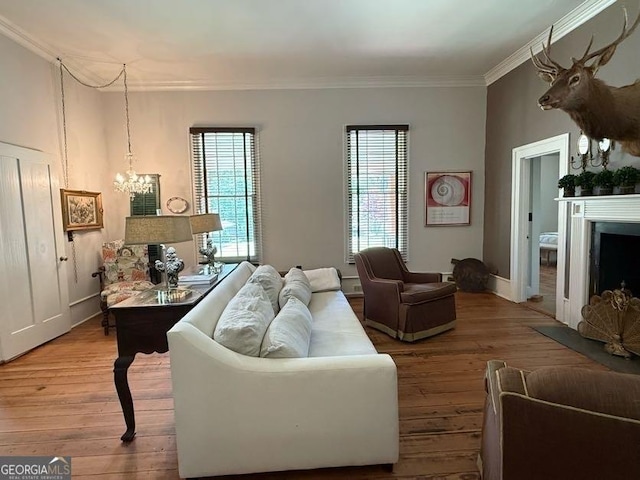 living area with hardwood / wood-style floors, a fireplace, an inviting chandelier, and ornamental molding
