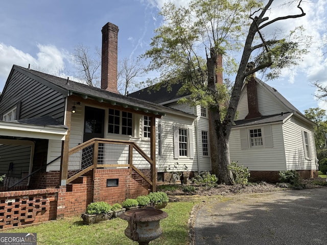 back of house featuring a chimney and stairs