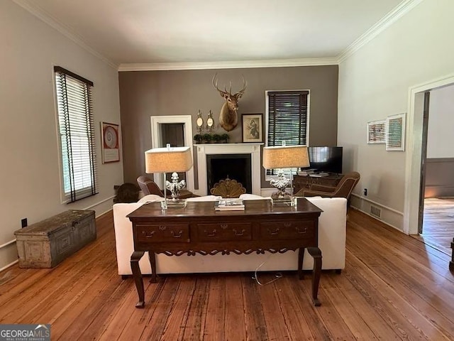 living area featuring a fireplace, wood finished floors, visible vents, and ornamental molding