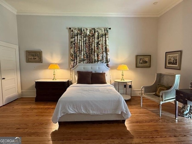bedroom with wood finished floors, crown molding, and baseboards