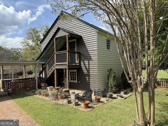 rear view of property featuring a lawn and stairway